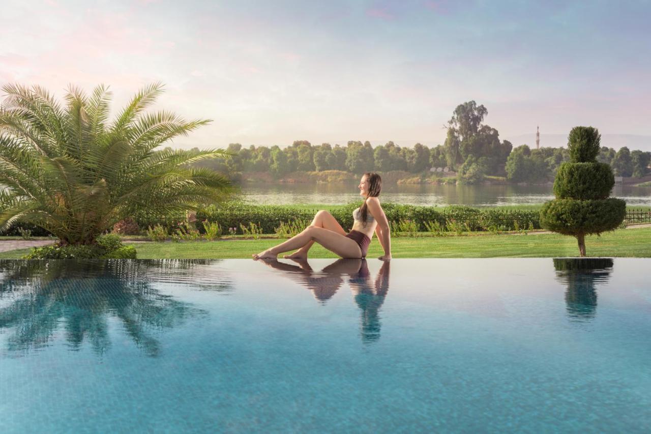Jolie Ville Hotel & Spa Kings Island Luxor Kültér fotó A woman sitting on the edge of a pool